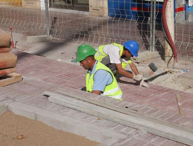 Dos obreros colocan el suelo de la zona exterior de las obras de la estaci&oacute;n del Metro./ Jose &Aacute;ngel Garc&iacute;a