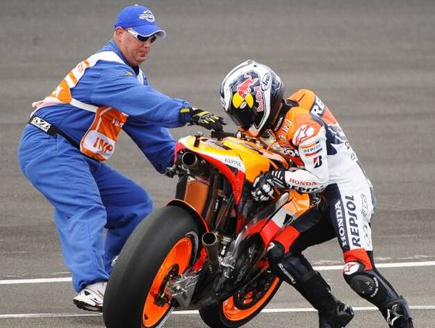 Dani Pedrosa levanta su motocicleta con ayuda de un juez de pista.
