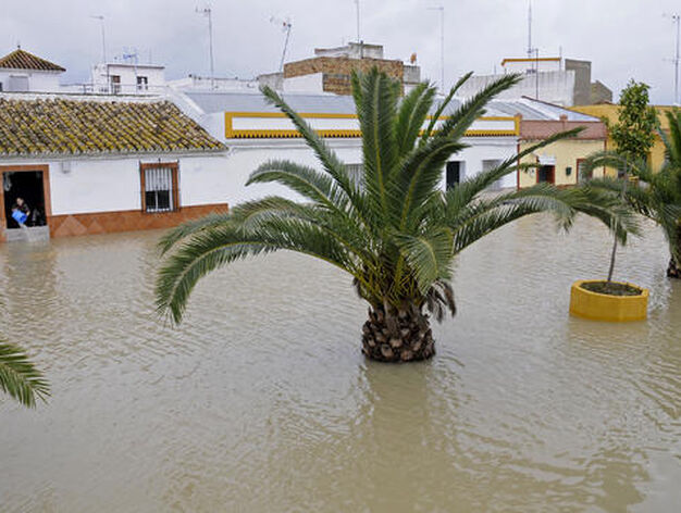 Una calle de Tocina inundada; al fondo, una mujer achicando agua.

Foto: Juan Carlos V&aacute;zquez