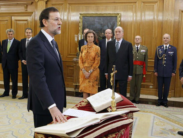 Rajoy pone la mano derecha sobre la Constituci&oacute;n ante Francisco Caama&ntilde;o, que ha actuado de Notario Mayor del Reino. / EFE