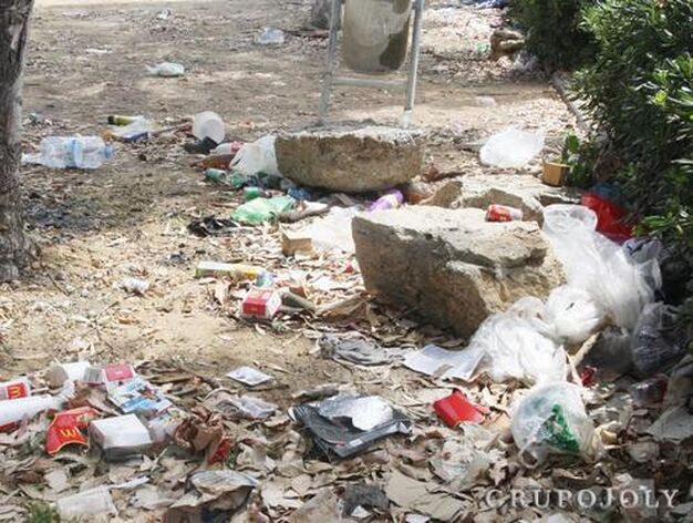 Pl&aacute;ticos y restos de suciedad esparcidos por el suelo del recinto frente a una papelera.

Foto: Paco Guerrero