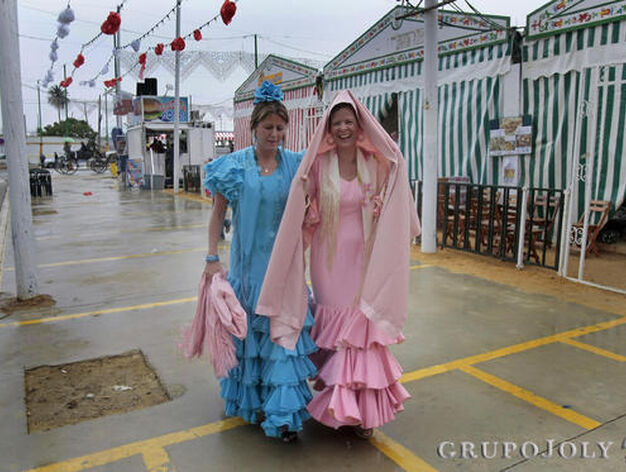 Dos mujeres ataviadas de flamenca se resguardan de la lluvia en una de las desiertas avenidas de Las Banderas durante la jornada de ayer.

Foto: Fito Carreto