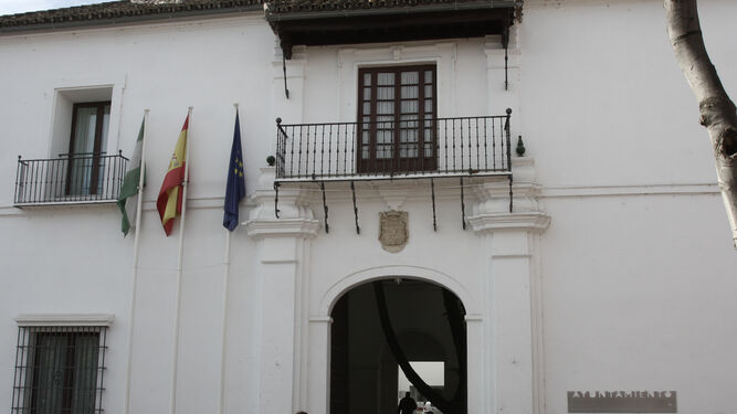 Un hombre pasa junto a la fachada del Ayuntamiento de Tomares.