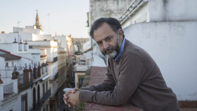 José Fernando Gabardón de la Banda, asomado a una terraza de la calle Sierpes, con la Giralda al fondo.
