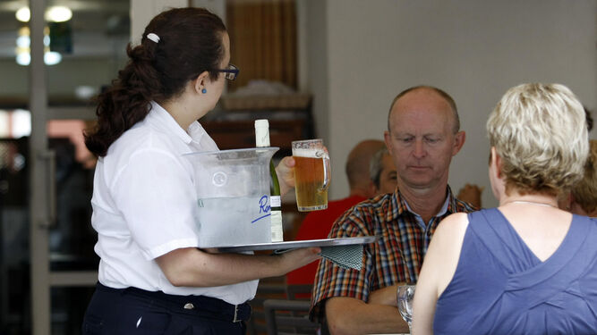 Una camarera atiende a unos turistas en un restaurante de Cádiz.