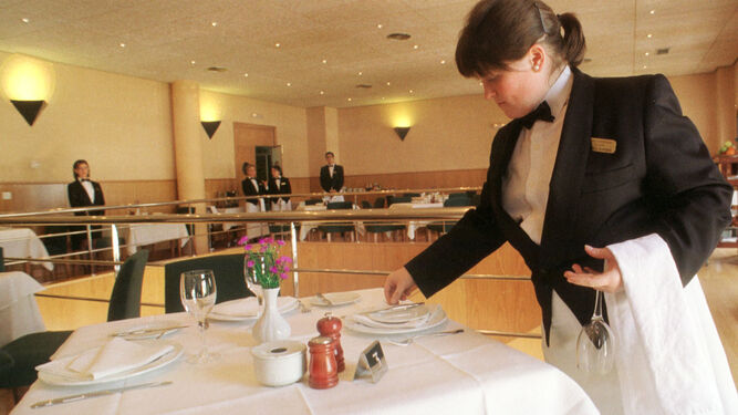 Una camarera poniendo la mesa en un salón de banquetes.