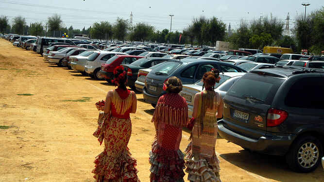 Tres mujeres vestidas de flamenca caminan por los aparcamientos del Charco de la Pava.