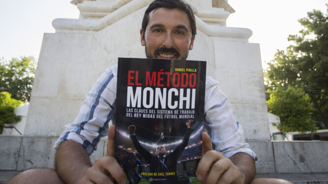 Daniel Pinilla posa con su libro, El método Monchi, en el pedestal de la estatua del rey San Fernando.