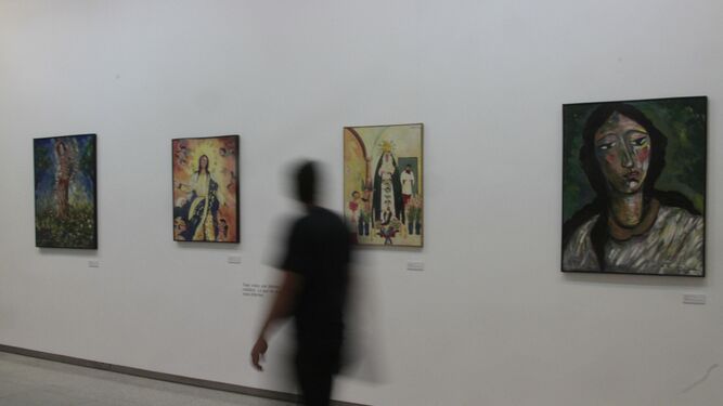 Un visitante pasea delante de algunos de los lienzos de Ocaña dedicados a las devociones religiosas.