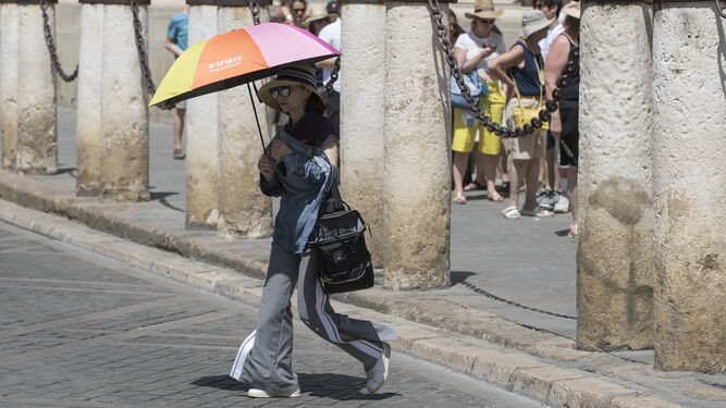 Una turista se protege del sol con una sombrilla.