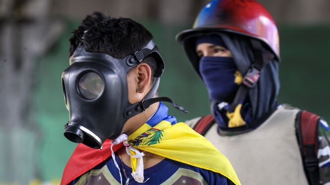 Dos jóvenes venezolanos tapan su rostro en las protestan contra Maduro.