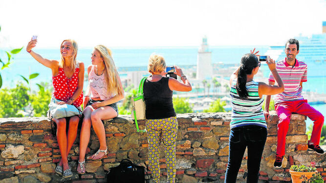 Un grupo de turistas se fotografía con la panorámica de Málaga al fondo.