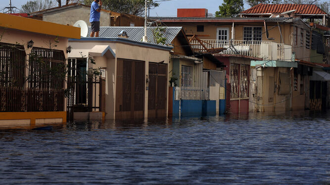 Un hombre realiza una llamada desde el tejado de una vivienda ubicada en una calle inundada de Santasucre.