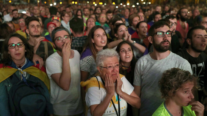 Parte de los concentrados escuchan con gestos de sorpresa y decepción el último tramo de la intervención de Puigdemont.