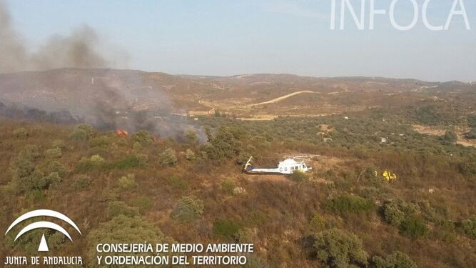 Un helicóptero del Infoca junto a la zona en la que se declaró el incendio de El Ronquillo.
