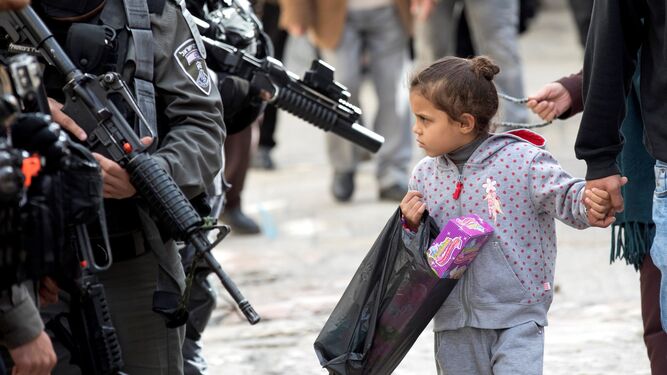 Una niña palestina con un juguete camina con sus padres junto a la Policía de Fronteras israelí, ayer en Jerusalén.