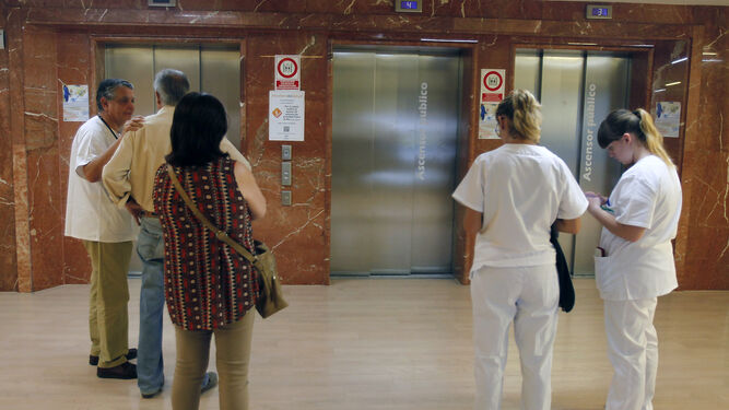 Usuarios y personal sanitario esperan en la zona de ascensores de un centro hospitalario.