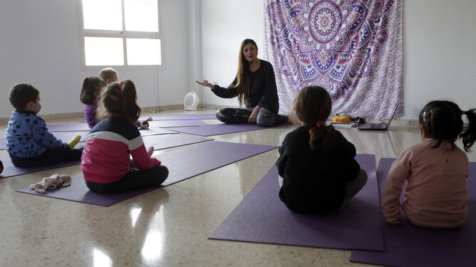 1. Los pequeños comparten un momento bonito del día antes de empezar la clase. 2. Raquel Piñero muestra una de las cartas de sus 'yoguicards', pensadas para trabajar el yoga con los niños y fomentar en ellos valores positivos, entre otras cosas.