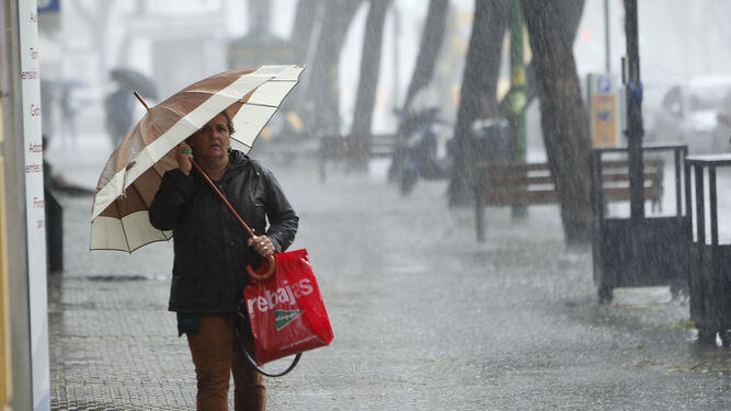 Una mujer camina bajo la fuerte lluvia en Sevilla