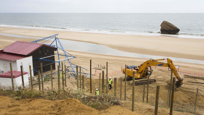 Varios trabajadores se afanan estos días en colocar las pasarelas que comunican la zona de dunas con la playa de Matalascañas.