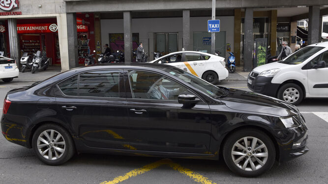 Un VTC pasa ante una parada de taxis, en el centro de Sevilla.