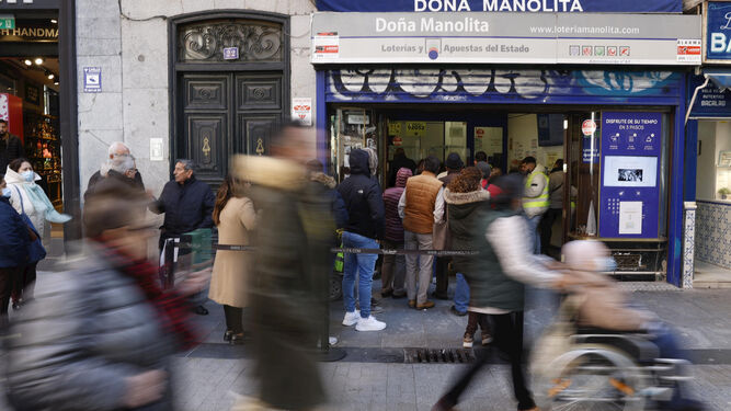 Varias personas hacen cola para comprar décimos de Lotería para el sorteo navideño de El Gordo en la Puerta del Sol de Madrid.