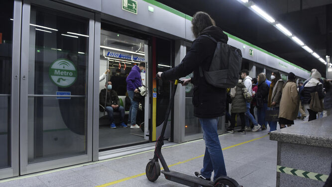 Una joven junto con su patinete eléctrico en una estación de Metro de Sevilla