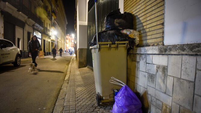 Un cubo de basura individual junto a una bolsa abandonada en una céntrica calle.