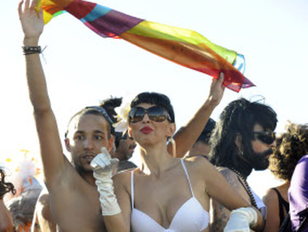 Dos de los participantes en la marcha levantan una bandera arco iris.