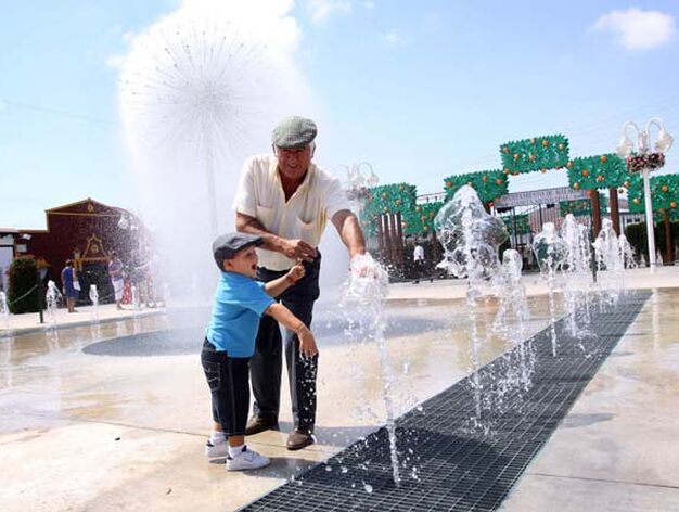 Abuelo y nieto se refresan en la fuente instalada en el Real de la Feria.
FOTO: Migue Fern&aacute;ndez