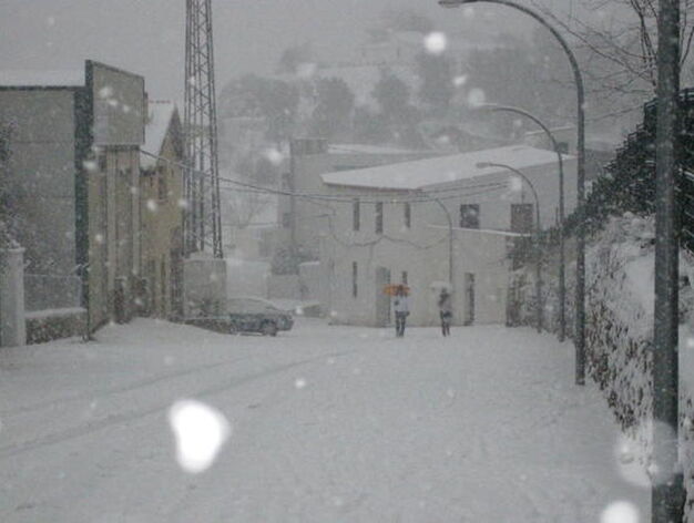 Dos j&oacute;venes caminan, parag&uuml;as en mano, para cubrirse de la nevada.

Foto: C. Valdivieso