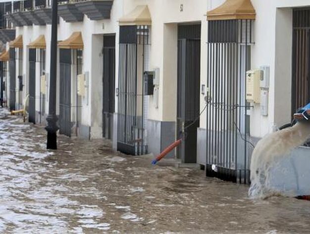 Una calle de Lora del R&iacute;o inundada, y un vecino achicando agua con un cubo.

Foto: Agencias