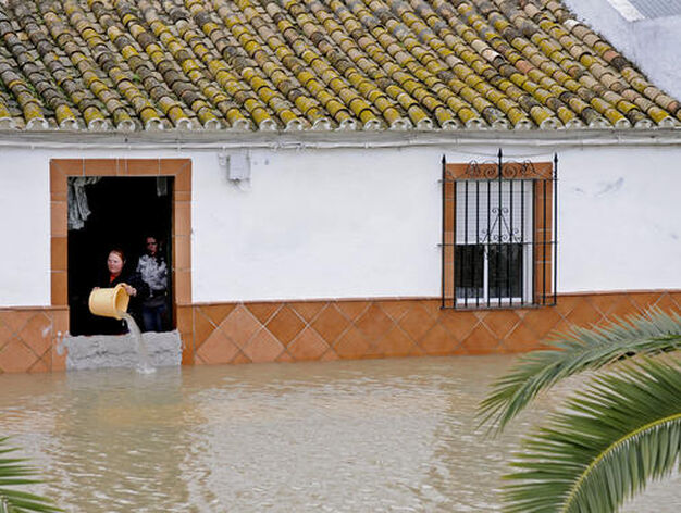 Una mujer achica el agua que inunda su casa con un cubo (Tocina).

Foto: Juan Carlos V&aacute;zquez