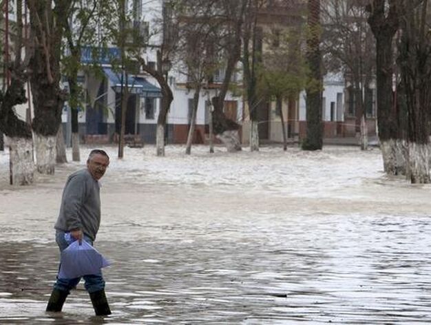 Un hombre sostiene una bolsa y anda sobre el agua que inunda Lora del R&iacute;o.

Foto: Agencias