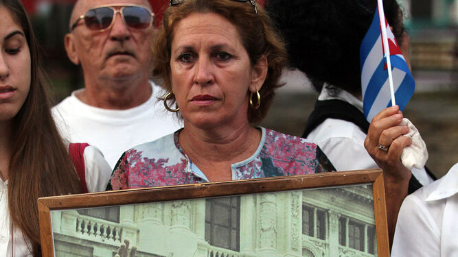 Una mujer muestra una fotografía de Fidel Castro y Hugo Chávez.