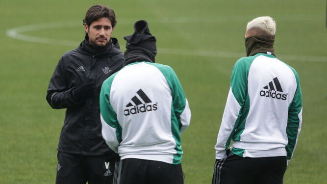 Víctor dialoga con Dani Ceballos y otro jugador bético, bien protegidos del frío, en la sesión de ayer.