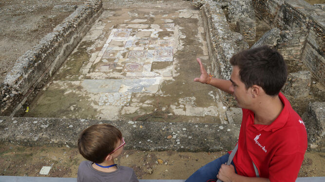 Un niño atiende las explicaciones sobre un mosaico de la ciudad romana.