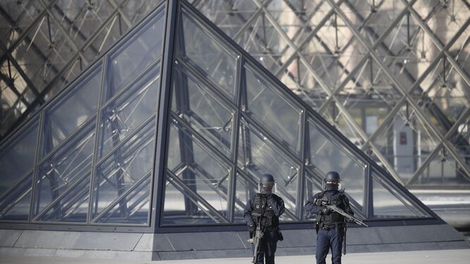 Dos policías armados vigilan los aledaños del Louvre.
