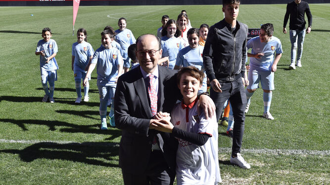 El presidente del Sevilla bromea en el césped con uno de los niños.