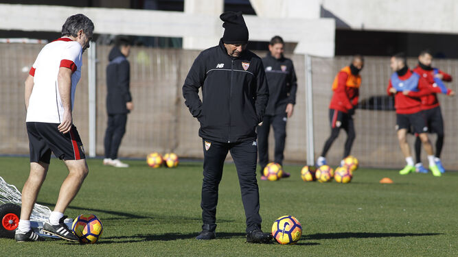 Jorge Sampaoli permanece pensativo sobre el césped mientras su ayudante Juanma Lillo, mucho menos abrigado, juega con un balón.