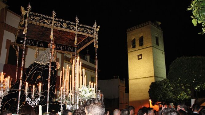 La Virgen de los Dolores en la Plaza del Calvario bajo su majestuoso palio de la Bajada con piezas del siglo XVIII y XIX. Al fondo, la torre de la parroquia.