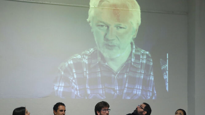 Irene Montero, Hervé Falciani y Miguel Urbán, entre otros, escuchan ayer por videoconferencia de Julian Assange en una charla en Madrid de evasión fiscal.