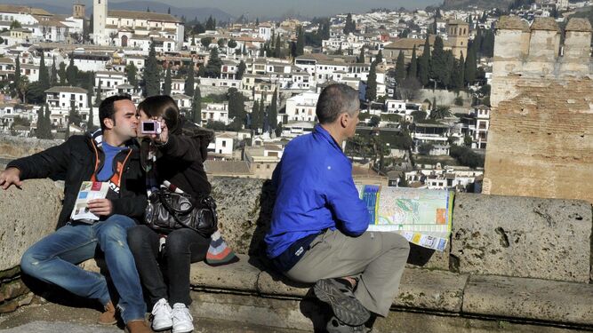 Unos turistas se fotografían en uno de los miradores del conjunto de la Alhambra, con el barrio del Albaicín al fondo.