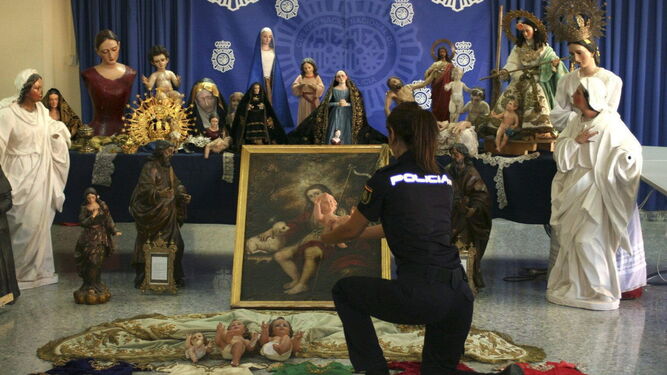 Una agente de la Policía Nacional prepara una exposición de obras de arte recuperadas en una investigación.