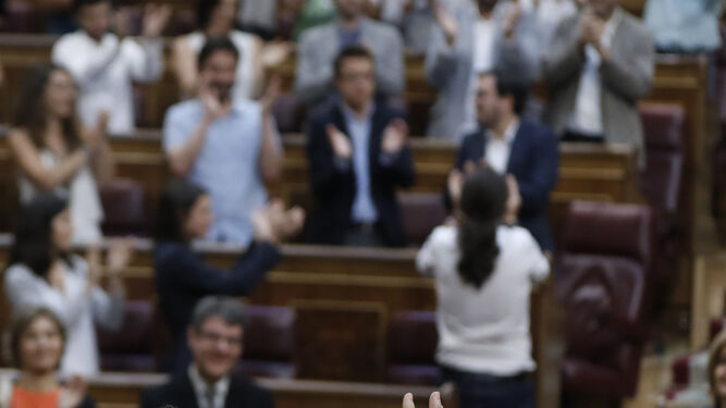 Rajoy aplaude, con Iglesias al fondo, tras la votación de la moción de censura.