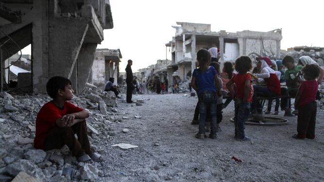 Varios niños sirios juegan entre las ruinas de una ciudad.