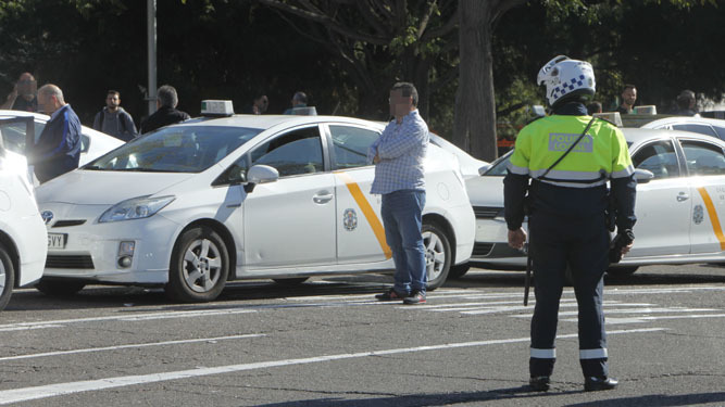 Un policía local observa a varios taxistas en la zona de la estación de Santa Justa.