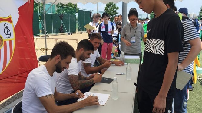 Los jugadores sevillistas Pareja, Banega y Carriço firman autógrados para los aficionados en Osaka.