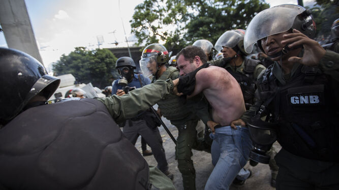 Agentes  de la Guardia  Nacional  Bolivariana detienen a un manifestante pro oposición en una protesta en Caracas .