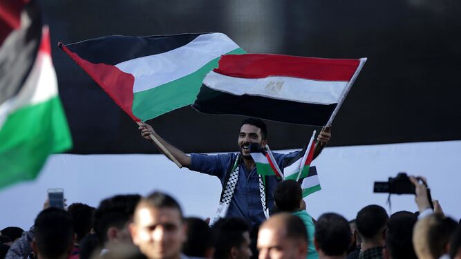 Un palestino ondea en Gaza banderas de Palestina y Egipto durante la celebración del acuerdo entre Hamás y Al Fatah alcanzado ayer en El Cairo.
